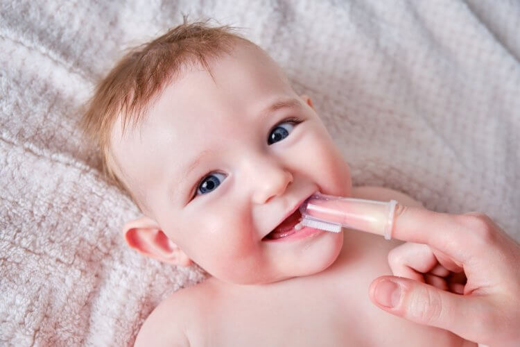 Mother Hands Brushing Teeth With A Finger Skim Of A Infant Baby