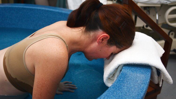 A Pregnant woman has painful contractions during a natural water birth.